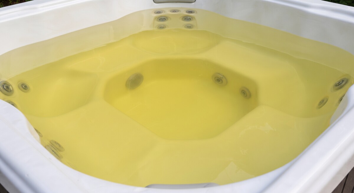 Vue rapprochée d'une eau de spa au brome jaunie mais transparente, avec la coque claire du bassin visible.
